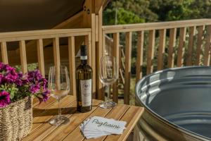 a bottle of wine sitting on a table with wine glasses at Glamping Pagliaini in Riparbella