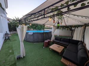 a patio with a couch under a tent with a pool at Vincents Paradise in Mairena del Aljarafe