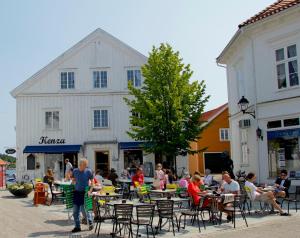 grupa ludzi siedzących przy stołach przed budynkiem w obiekcie Grimstad Vertshus w mieście Grimstad
