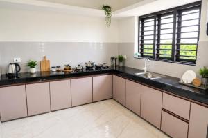 a kitchen with white cabinets and black counter tops at Sidra Apartments - Spacious 2BHK Family Stay in Nilgiris, Pandalur, Tamil Nadu in Pandalūr