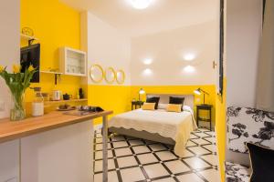 a bedroom with a bed and a kitchen with yellow walls at Suite Home Milano Fiera in Milan