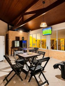 a dining room with a table and chairs and a tv at Mansão Ouro Verde Beira Mar in Piçarras