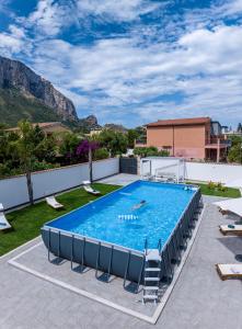 a swimming pool with chairs and a mountain in the background at Villa Yasmine in Cinisi
