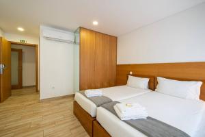 a bedroom with two beds with white sheets at Central Suítes 1 in São João da Madeira