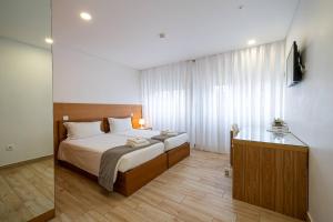 a bedroom with a bed and a desk in it at Central Suítes 1 in São João da Madeira
