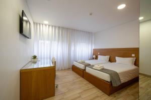 a bedroom with a bed and a desk in it at Central Suítes 1 in São João da Madeira