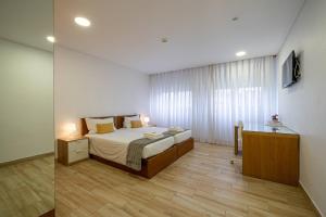 a bedroom with a bed and a desk in it at Central Suítes 1 in São João da Madeira +7 photos
