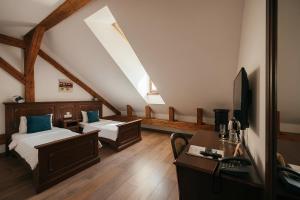 a attic room with two beds and a desk and a television at Casa Chitic Hotels in Braşov