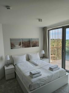 a white bedroom with a large bed with two lamps at Pinea Apartments in Pobierowo +134 photos