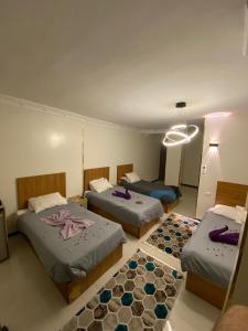 a hotel room with three beds and a chandelier at 3pyramids view inn in Cairo