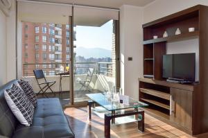 sala de estar con sofá y TV de pantalla plana en Norus Apartments Las Condes, en Santiago