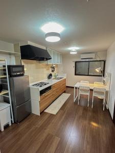 a kitchen with a stove and a table with chairs at COMMA House 川崎 in Kawasaki