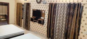 a room with a tv on a wall with curtains at Prithviraj palace in Shahdol