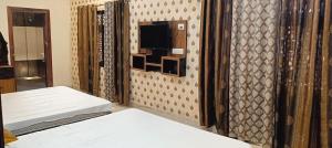 a room with two beds and a tv on a wall at Prithviraj palace in Shahdol