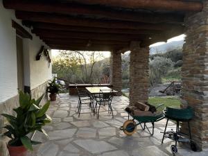 a patio with a table and chairs and a stone wall at Alpujarra Las Lindes in Pórtugos