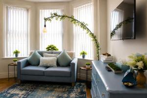 a living room with a blue couch and windows at Lavina by the sea in Bangor +3 photos