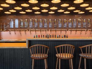 a bar with three chairs in front of a counter at ScanHotels Stadthafen in Rostock