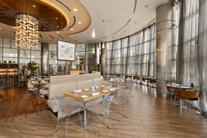 a restaurant with tables and chairs and a chandelier at Novotel Abu Dhabi Gate in Abu Dhabi