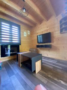 a living room with a table and a tv at Mon chalet dans le Jura in Saint-Laurent-en-Grandvaux