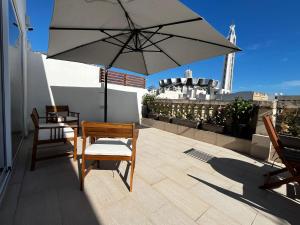 a patio with two chairs and an umbrella on a roof at Central Hostel Malta in Birkirkara