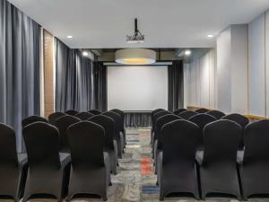 a conference room with black chairs and a screen at Mercure Jayapura in Jayapura