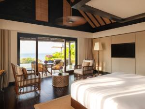 a bedroom with a bed and a living room with a balcony at Raffles Bali in Jimbaran