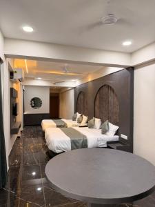 a hotel room with three beds and a table at Hotel J K Town in Ahmedabad