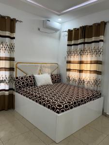 a small bed in a room with curtains at Mitty Residence in Conakry
