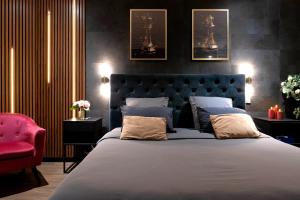 a bedroom with a large bed and a red chair at Love Room Lorient - Le King Size - Balnéo 2 places in Lorient