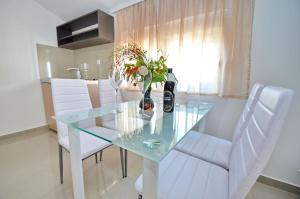 a dining room table with a glass top and white chairs at Villa Velzon Lux in Budva
