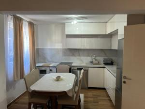 a kitchen with a table and a table and chairs at Home DINA in Ilidža