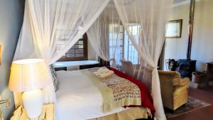 a bedroom with a canopy bed and a chair at DeKotzenhof in Wakkerstroom