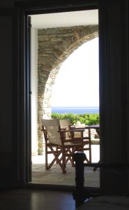 an open door to a patio with a chair and a table at Rosalie Home - Aegean Deck in Tinos
