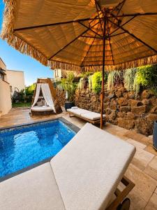 an umbrella sitting next to a swimming pool with aitating at Villa Naama in Qasrîne