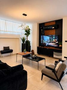 a living room with a couch and a flat screen tv at Villa Naama in Qasrîne