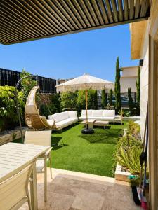 a garden with white furniture and an umbrella at Villa Naama in Qasrîne