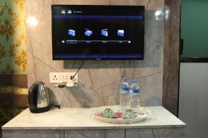 a television on a wall with bottles of water and cookies at Hotel Royal Sen in Lālbhitti