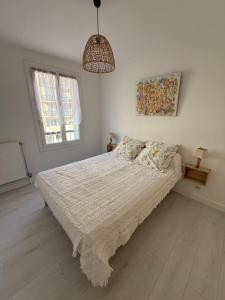 a white bedroom with a bed and a window at Les 3 Pigeons in Narbonne