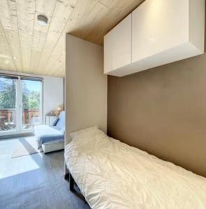 a bedroom with a bed and a white cabinet at Studio montagne Les Carroz in Arâches-la-Frasse