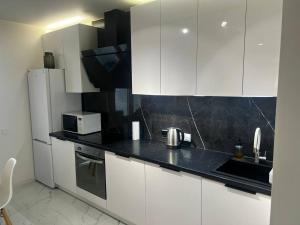 a kitchen with white cabinets and a black counter top at Апартаменти La Familia в Одеський Бульвар - Od 433 in Teremki +4 photos