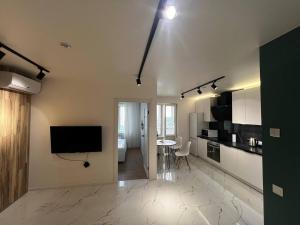 a living room with a television and a kitchen with a table at Апартаменти La Familia в Одеський Бульвар - Od 433 in Teremki