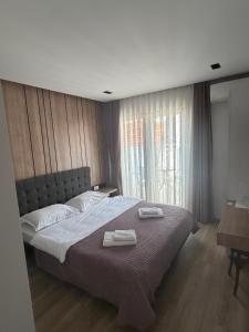 a bedroom with a large bed with two towels on it at L'Hotelpz in Prizren