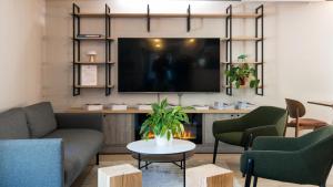 a living room with a couch and chairs and a tv at Campanile NATURE - Lille Wasquehal in Wasquehal