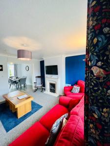 a living room with a red couch and a table at Bright & Sociable Home with Garden Retreat in Capel Saint Mary
