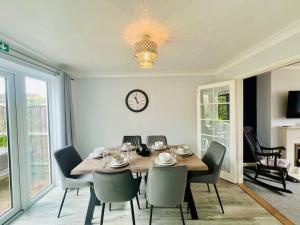 a dining room with a table and chairs and a clock at Bright & Sociable Home with Garden Retreat in Capel Saint Mary