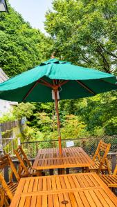 a green umbrella sitting on top of a wooden table at A forest guesthouse with barbecue facilities in Nikko
