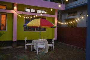 a table with a colorful umbrella in front of a house at The Backpackers Hostel in Guwahati +15 photos