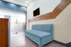 a blue chair in a room with a tv at Super Townhouse Krishna Nagar Metro Station in New Delhi