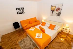 a bedroom with an orange bed and a couch at House Roso in Makarska