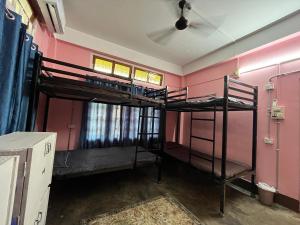 two bunk beds in a room with pink walls at The Backpackers Hostel in Guwahati